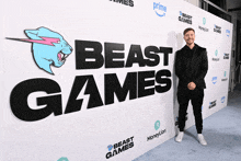 a man stands in front of a wall that says " beast games "