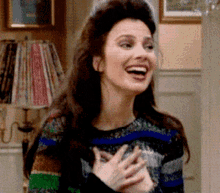 a woman is smiling and holding her hands to her chest
