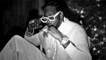 a black and white photo of a man wearing white sunglasses
