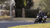 a man riding a motorcycle in front of a fence with a sign that says warning