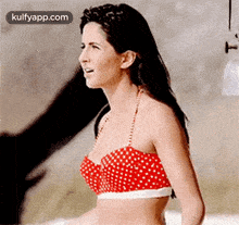 the woman is wearing a red and white polka dot bikini top .