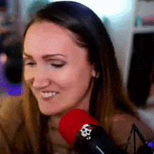 a woman is smiling in front of a microphone with the letter b on it