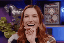 a woman with red hair is smiling in front of a spelljammer poster