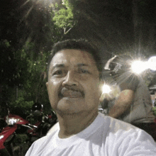 a man with a mustache is taking a selfie in front of some motorcycles