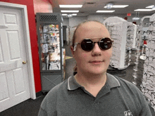 a man wearing sunglasses and a jb shirt stands in an optical store