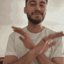 a man with a beard and a white shirt is clapping his hands