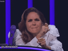a woman in a white shirt is holding a ring in her hand and has the name lialmeida05 on the bottom right