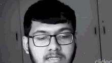 a man with glasses and a beard is making a funny face .