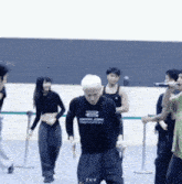 a man in a black shirt with the letter b on it is dancing in front of a group of people