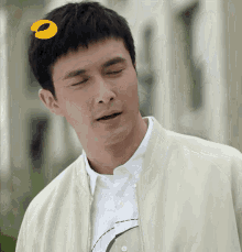 a man with his eyes closed has a yellow circle on his forehead