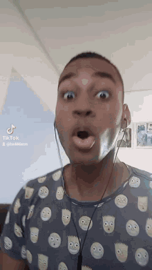 a man wearing a shirt with bart simpson faces is making a funny face
