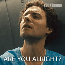 a man in a blue scrub says " are you alright " in front of a countdown logo