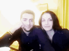 a man and a woman are posing for a picture and the woman has her hand on the man 's chin