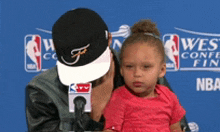 a man is holding a little girl in front of a sign that says nba