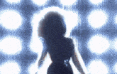 a woman in a black dress is standing in front of a blue background