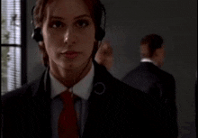 a woman in a suit and tie is wearing a headset .