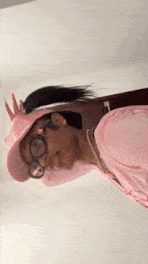 a woman wearing a pink hat and glasses is taking a selfie