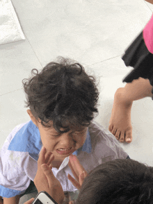 a little boy with curly hair is crying while being held