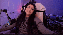 a woman wearing headphones and glasses is sitting in front of a microphone in a room .