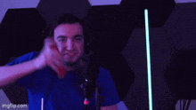 a man in a blue shirt is sitting in front of a microphone and making a funny face .