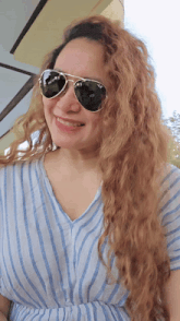 a woman wearing a striped shirt and sunglasses smiles