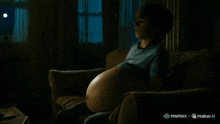 a pregnant woman is laying on a couch with a huge belly
