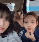 two girls are sitting in the back seat of a car .