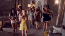 a group of women are standing in a room holding a chair and laughing .