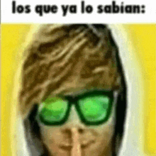 a man wearing sunglasses and a hoodie is making a shhh sign .