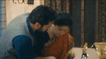 a man and a woman are sitting at a table and the man is kissing the woman on the neck .