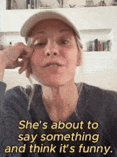 a woman wearing a hat is talking about something and thinks it 's funny