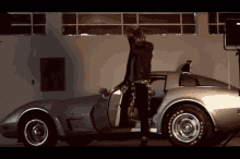 a man is standing next to a car with goodyear tires