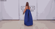 a woman wearing a traditional korean dress is dancing in front of a wall .