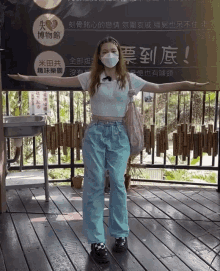 a woman wearing a mask stands in front of a sign that says ' a ' on it