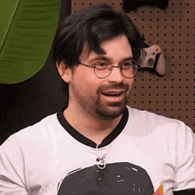 a man with glasses and a beard wears a white shirt with a picture of a planet on it