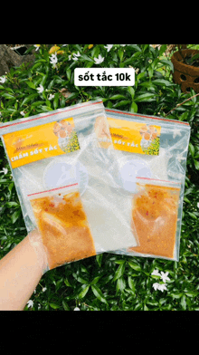 a person is holding two plastic bags of food with a yellow label that says sot tac 10k