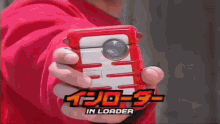 a person in a red hoodie is holding a red and white device in their hand .