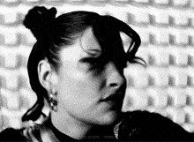 a black and white photo of a woman 's face with a bun in her hair .