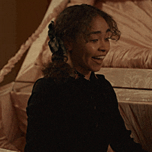 a woman with curly hair is smiling in front of a coffin