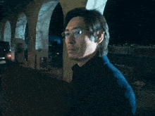 a man wearing glasses and a blue shirt looks at the camera