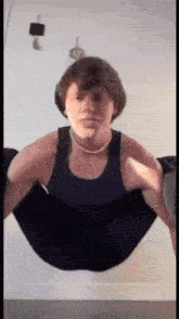a man in a black tank top is doing a yoga pose