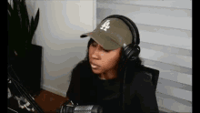 a woman is wearing headphones and a hat while sitting in front of a microphone .