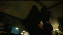 two people are fighting in a dark room with a lamp in the corner