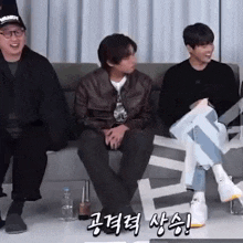 a group of men are sitting on a couch and laughing .