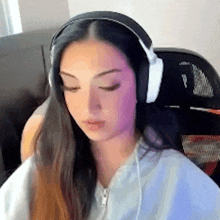 a woman wearing headphones is sitting in a chair looking down .