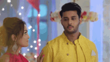 a man in a yellow jacket and a woman in a red dress are looking at each other