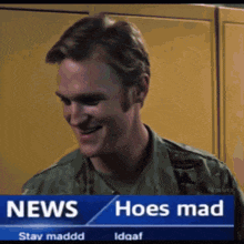 a man in a military uniform is smiling in front of a news screen that says news hoes mad