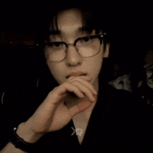 a man wearing glasses and a black shirt with the letter x on his chest