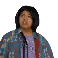 a young man singing into a microphone while wearing a colorful jacket