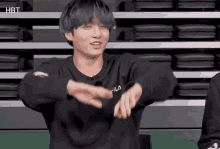 a man wearing a black fila sweatshirt is making a gesture with his hands